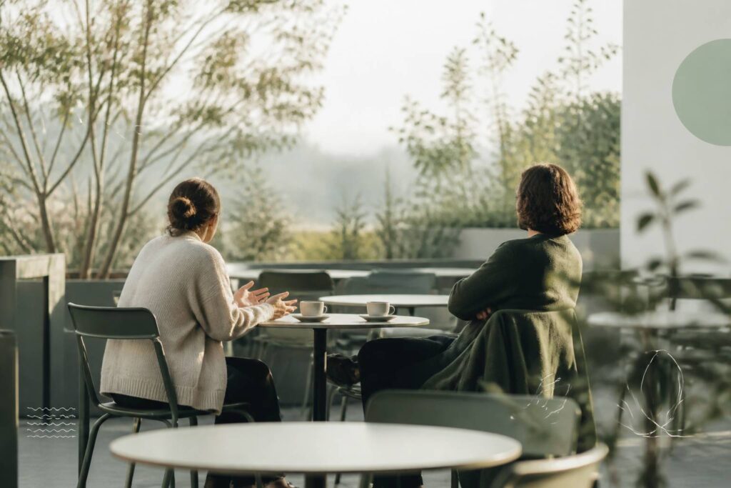 Deux personnes de dos à une table de café, l'une distante et méfiante