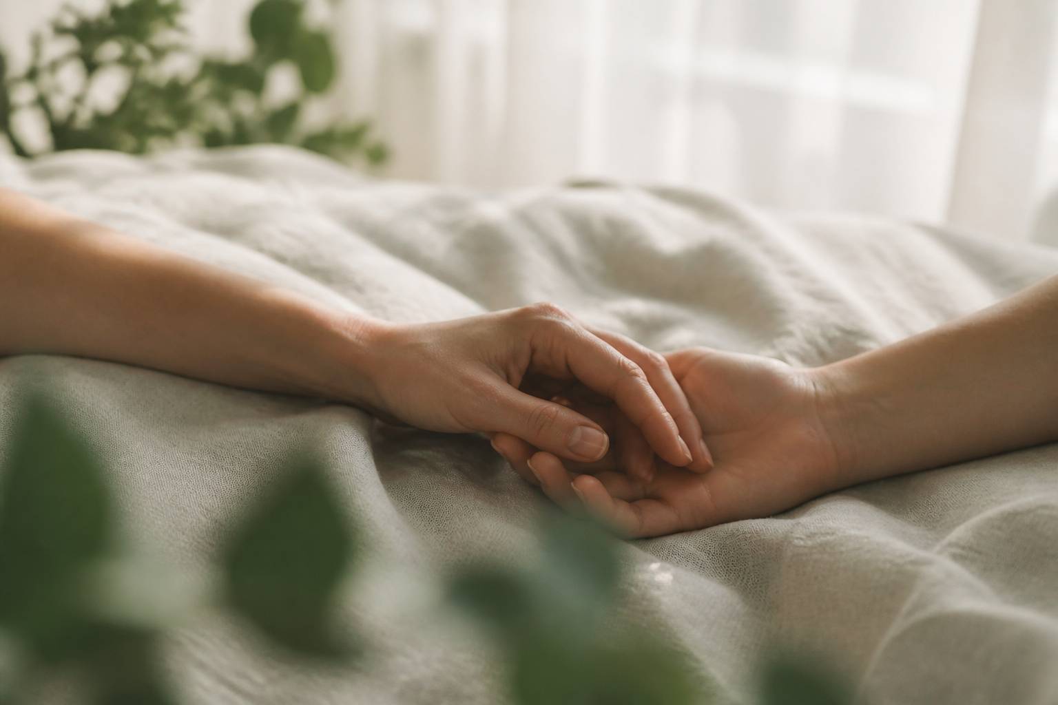 Deux mains qui se rejoignent doucement sur un drap clair