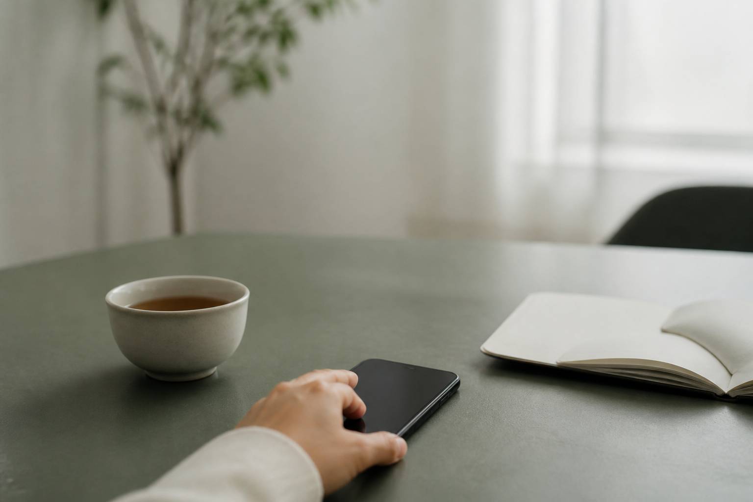 Téléphone posé face contre table à côté d'une tasse