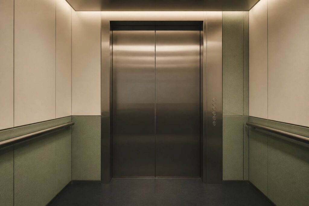 Cabine d'ascenseur vide aux portes fermées, ambiance calme aux lumières douces