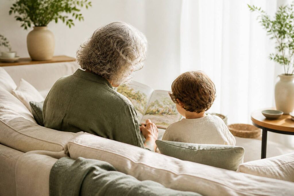 Grand-parent et enfant lisant un livre ensemble sur un canapé en lin